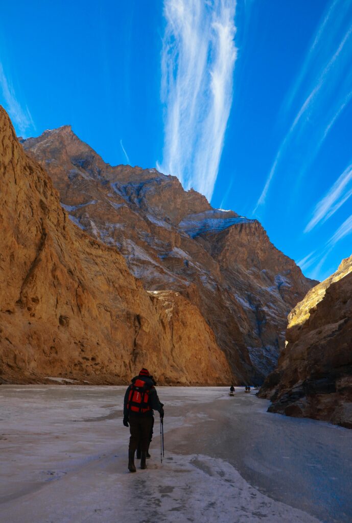 pexels-photo-6852852-6852852 A hiker walks through the stunning Zanskar Valley with dramatic blue skies and towering cliffs.